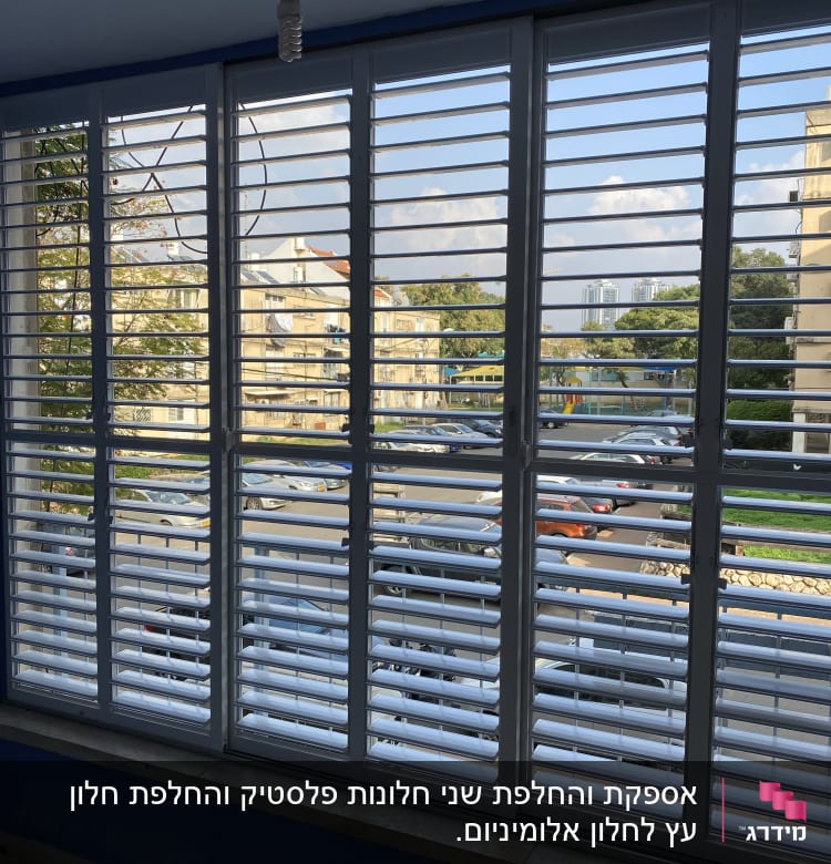 תריסים לבנים על חלון גדול עם נוף עירוני